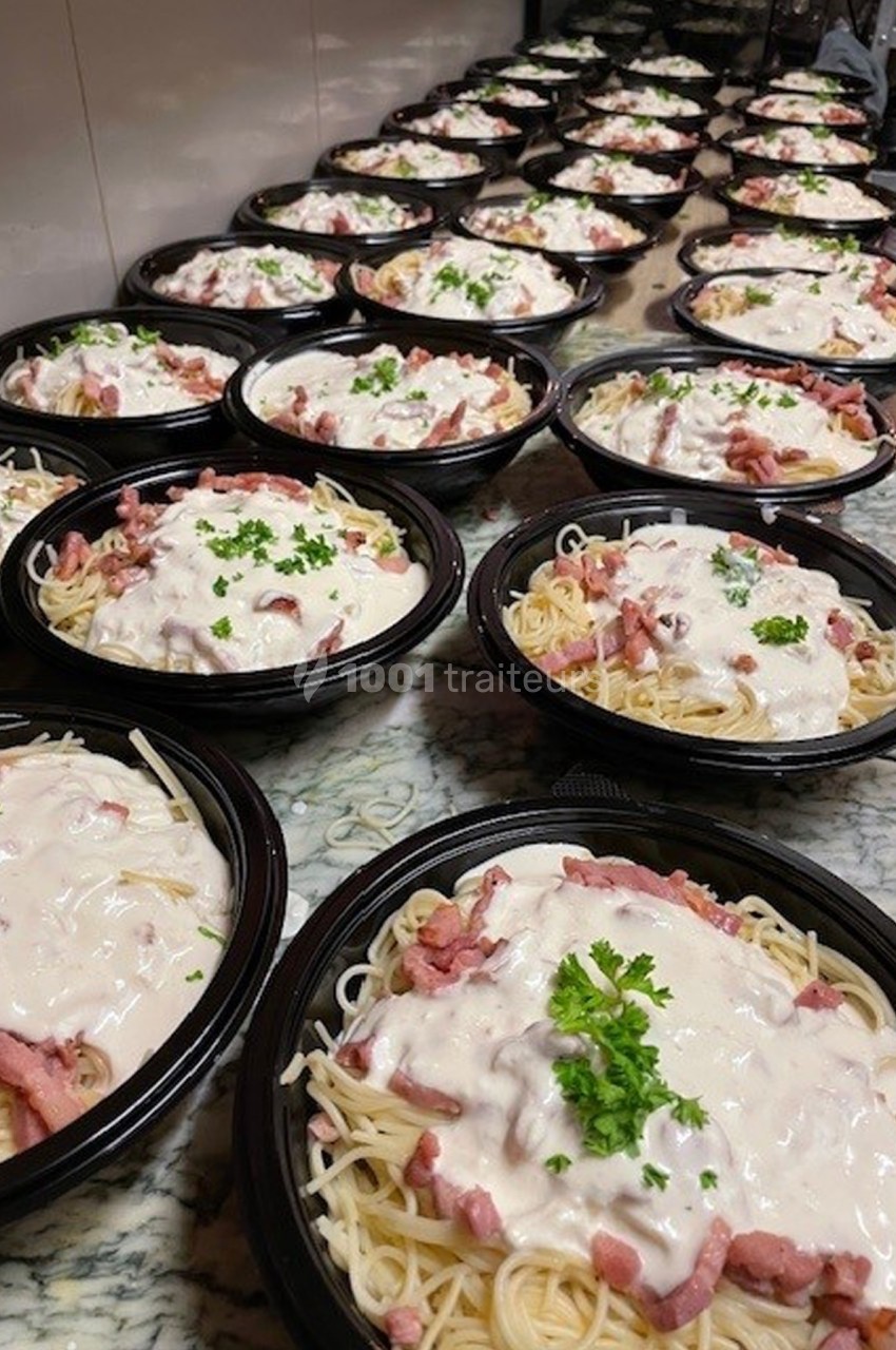 Plusieurs assiettes de spaghettis à la sauce blanche avec lardons, garnies de persil, alignées sur un plan de travail.
