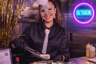 Burger au saumon fumé avec laitue, tomate et sauce, posé sur une table en marbre avec citron vert et herbes en arrière-plan.