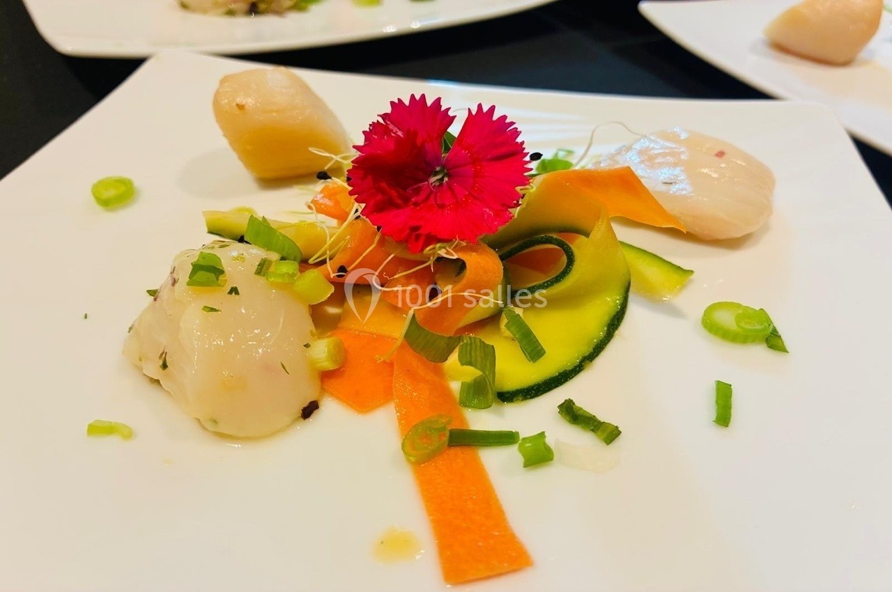 Assiette de carpaccio de Saint-Jacques avec légumes colorés, fleur comestible et ciboulette ciselée.