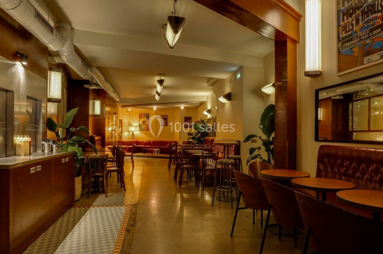 Salle de restaurant chaleureuse avec tables en bois, banquettes en cuir, éclairage tamisé et décoration rétro.