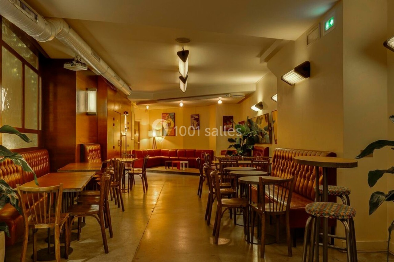 Salle de restaurant avec tables en bois, banquettes rembourrées, plantes décoratives et éclairage chaleureux.