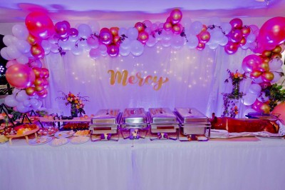 Miniature Location salle Triel-sur-Seine (Yvelines) - Malar évenements #65 Buffet décoré avec des ballons roses et blancs, plats variés, et un cochon rôti sur une table drapée de blanc.