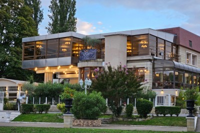 Groupe de personnes rassemblées en extérieur près d'une rivière, entourées de verdure et de stands d'exposition.