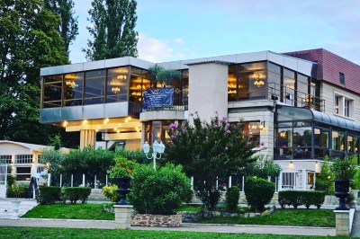 Groupe de personnes rassemblées en extérieur près d'une rivière, entourées de verdure et de stands d'exposition.