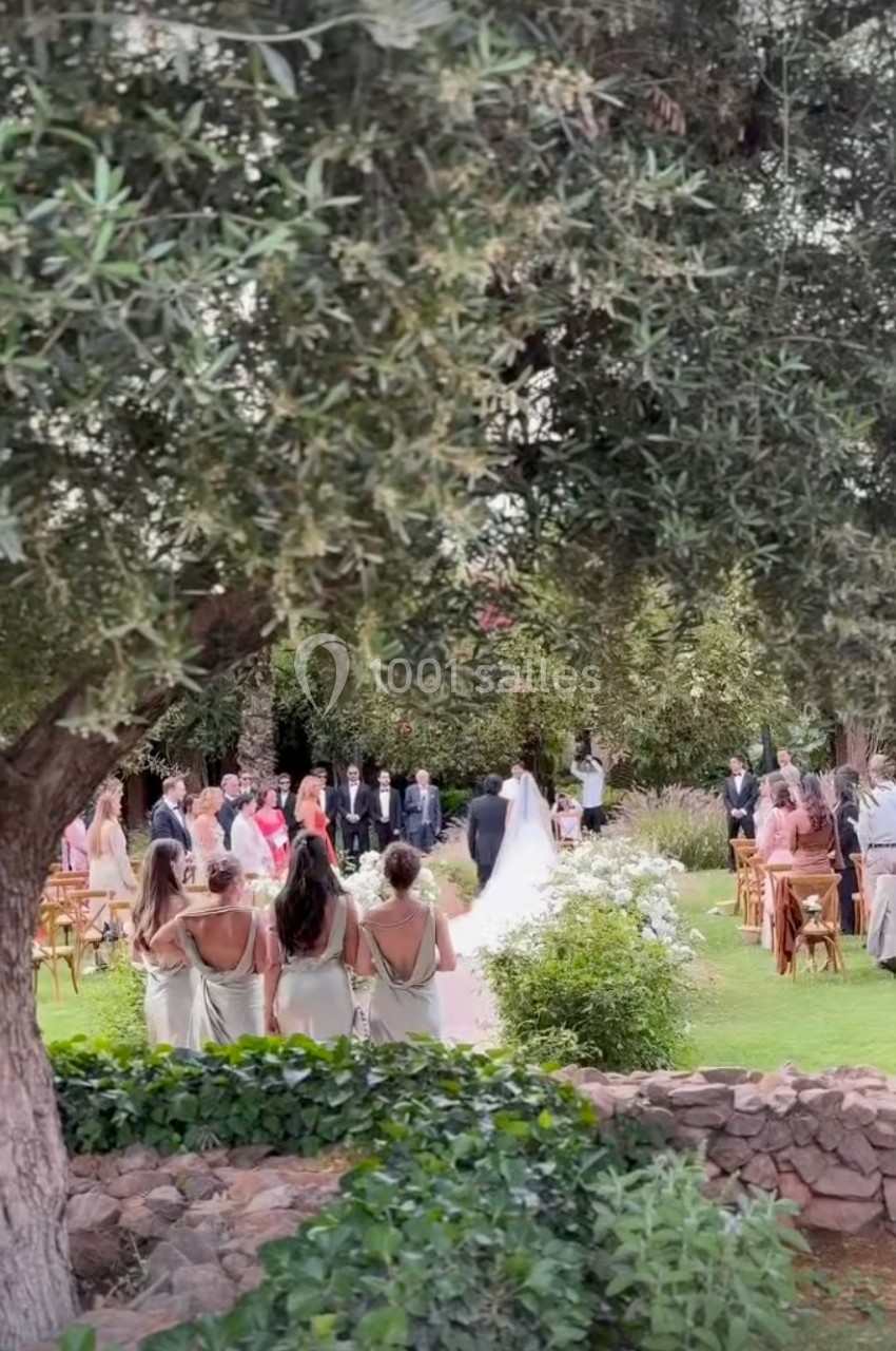Cérémonie de mariage en plein air avec des invités debout entourés de verdure et d'arbres.