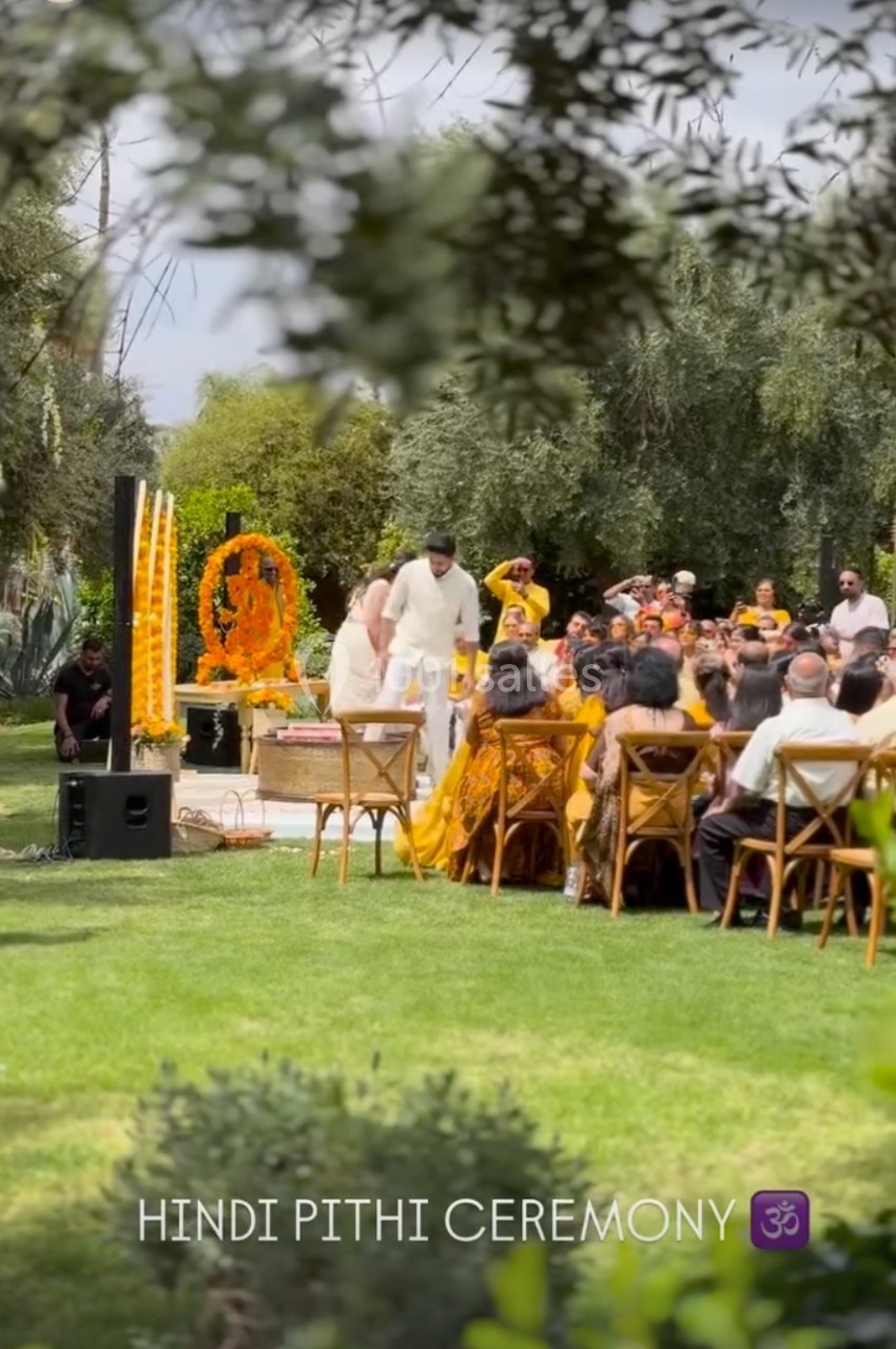 Cérémonie hindoue en plein air avec des participants assis, un couple au centre et des décorations traditionnelles.