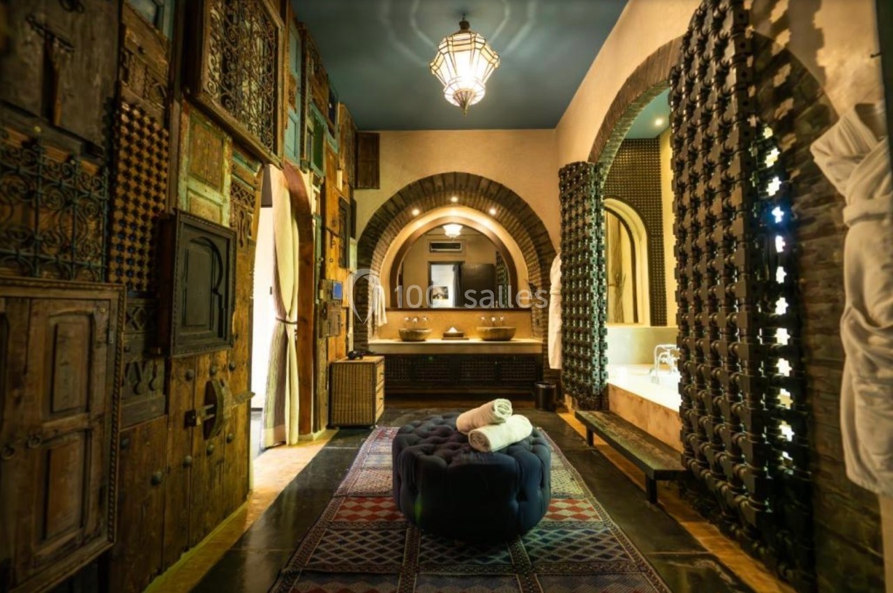 Salle de bain au style marocain avec arches, murs ornés de boiseries sculptées et baignoire intégrée.