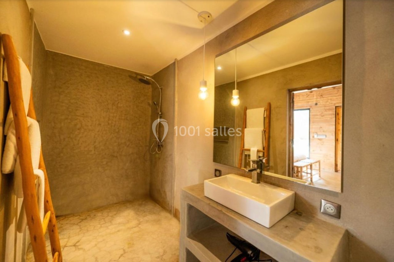 Salle de bain moderne avec douche à l'italienne, lavabo rectangulaire, miroir et échelle porte-serviettes en bois.