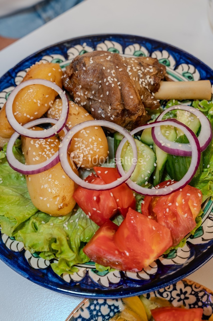 Assiette garnie de salade, tomates, concombres, rondelles d'oignon, pommes de terre et un morceau de viande avec graines de…