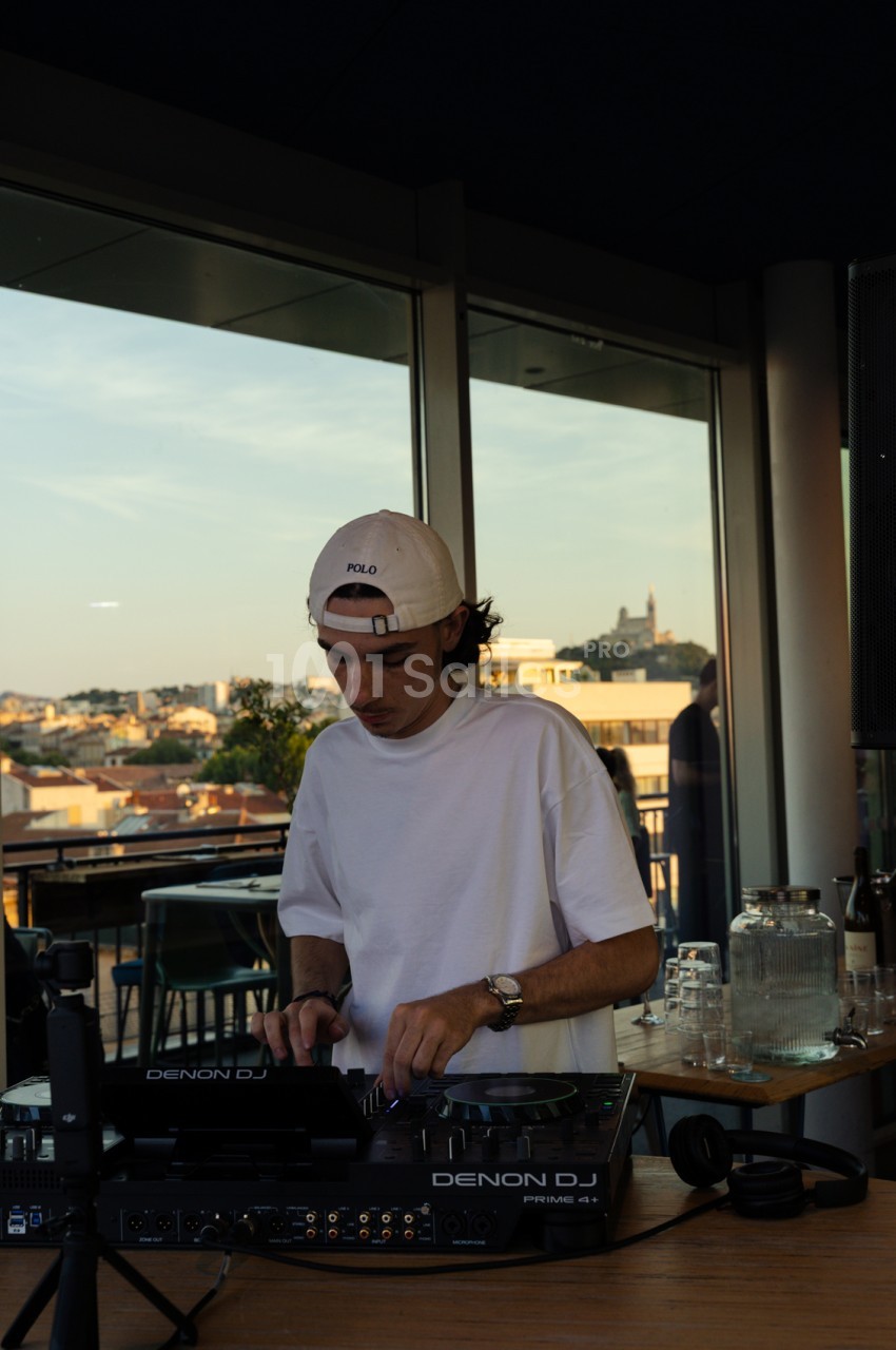 DJ en terrasse sur rooftop avec vue panoramique sur la ville de Marseille en arrière-plan.
