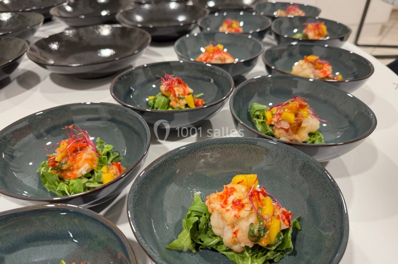 Assiettes contenant des entrées colorées à base de crevettes, mangue, roquette et garnitures, disposées sur une table.