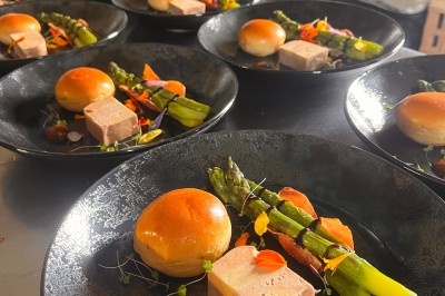 Assiette gastronomique avec foie gras, asperges, pain brioché et garnitures colorées, dressée pour un service en série.