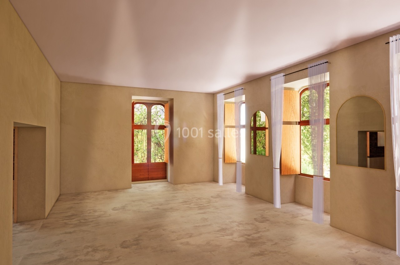 Salle lumineuse avec de grandes fenêtres cintrées, des rideaux blancs et des murs beige clair.