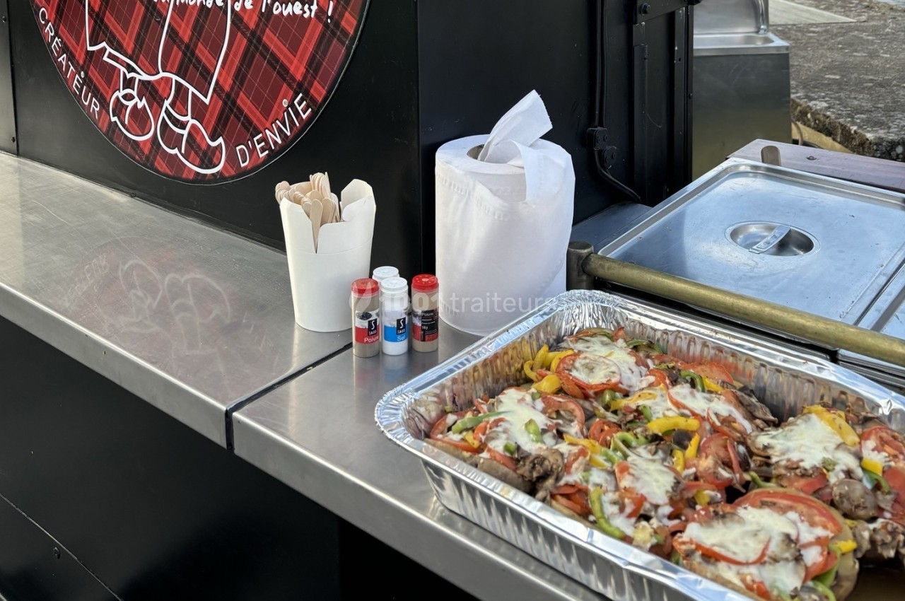 Plateau en aluminium contenant un plat cuisiné avec légumes, viande et fromage, posé sur un comptoir de food truck.