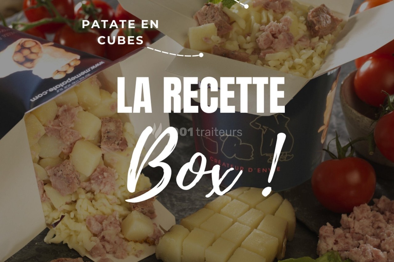 Boîte repas contenant des cubes de pommes de terre, fromage râpé et morceaux de viande, entourée de légumes frais.