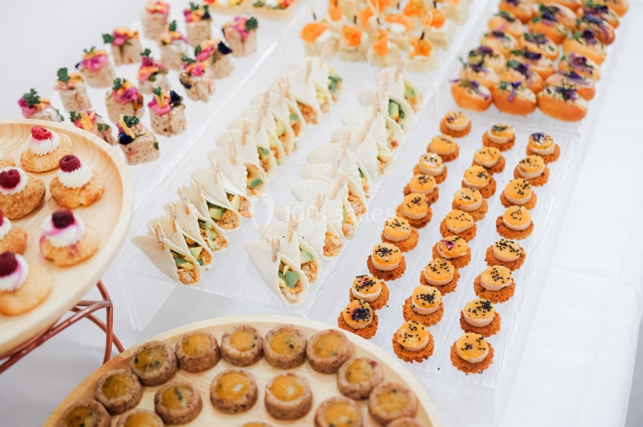 Plateau de canapés variés disposés sur des présentoirs, comprenant des bouchées salées et colorées.