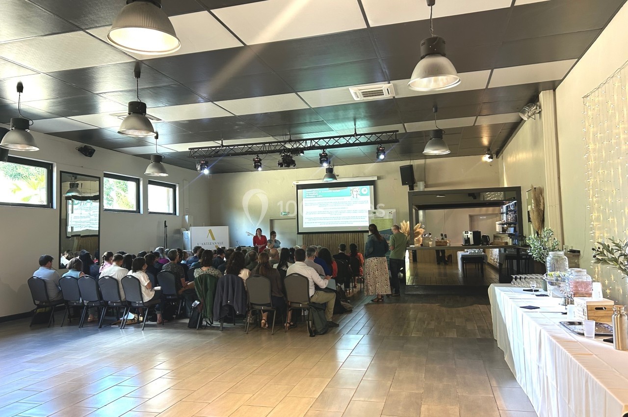 Salle de conférence lumineuse avec un groupe de personnes assises face à un écran de présentation.