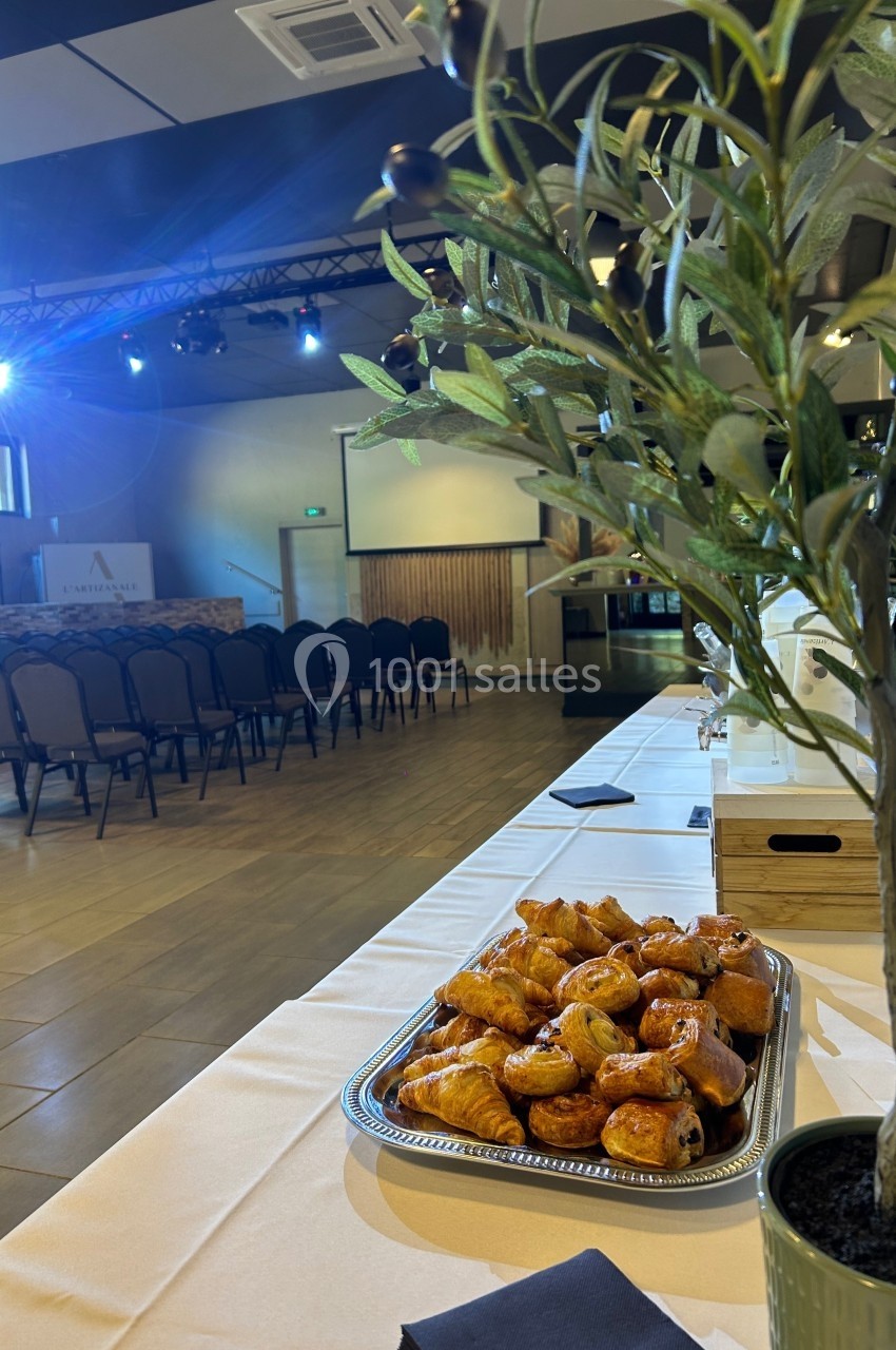 Plateau de viennoiseries sur une table, avec une salle de conférence aménagée et des chaises en arrière-plan.