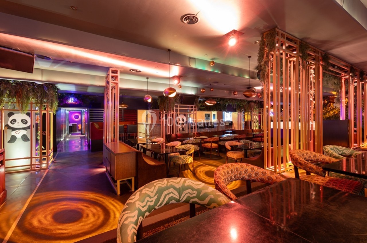 Salle de restaurant lumineuse avec des sièges colorés, des panneaux décoratifs et un éclairage tamisé.