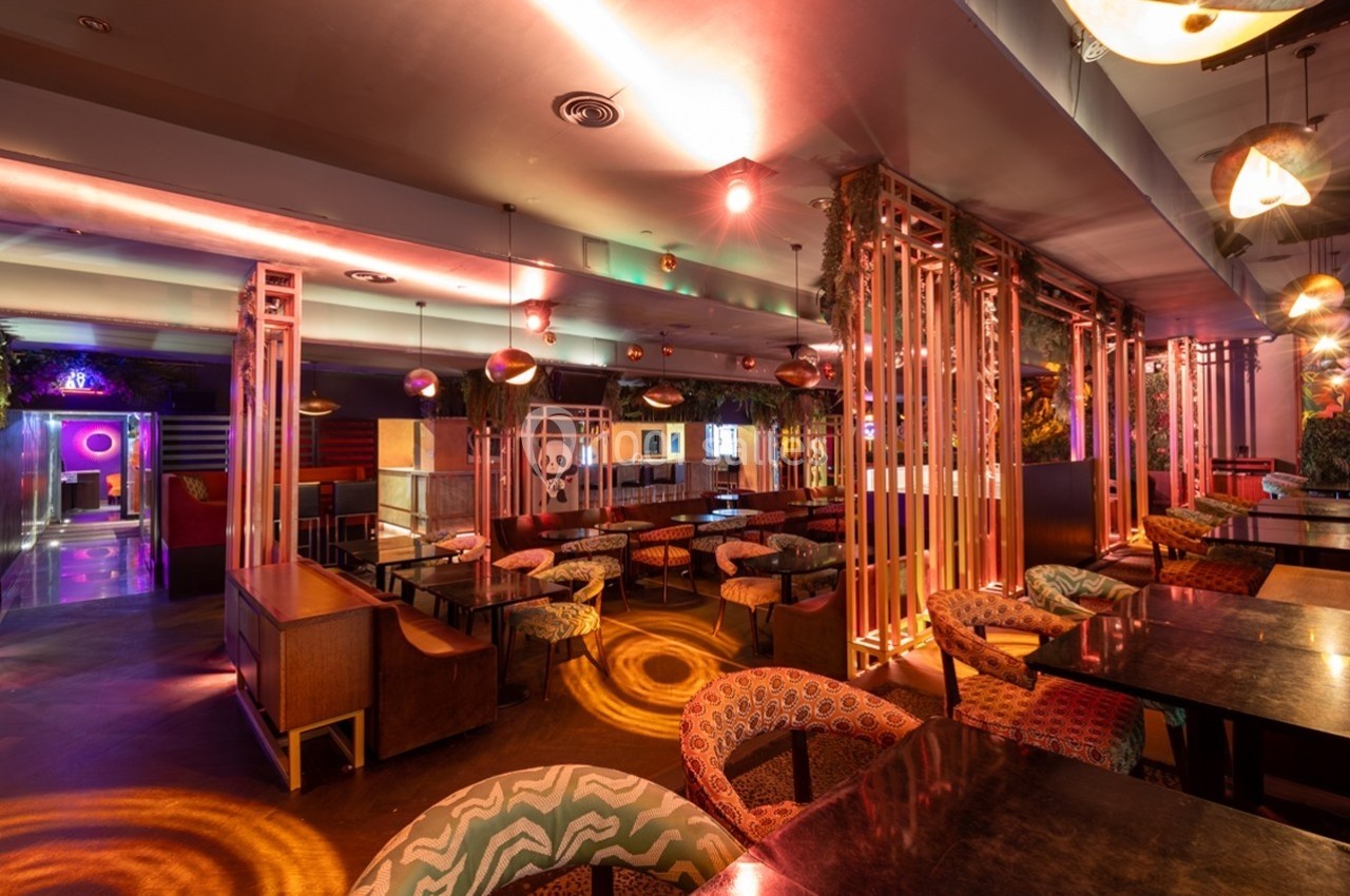 Salle de restaurant moderne avec éclairage tamisé, mobilier coloré et décoration contemporaine.