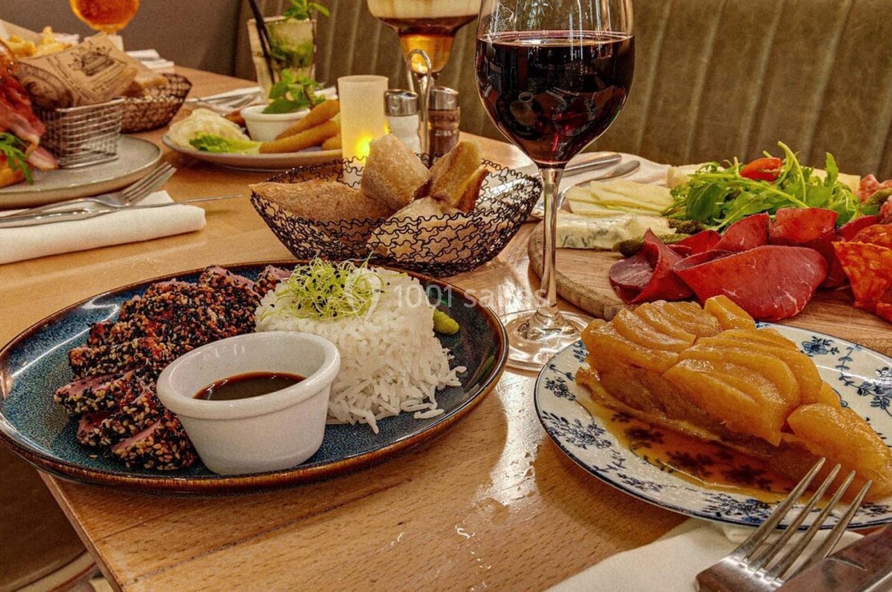 Repas composé de thon en croûte de sésame, riz, charcuteries, salade, pain, et tarte aux poires, avec un verre de vin rouge.