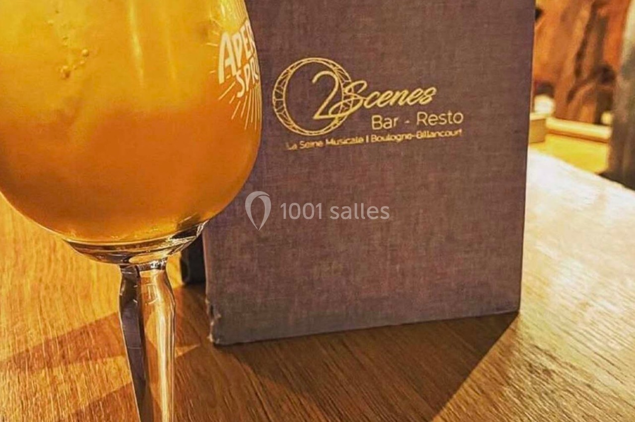 Verre de cocktail orange sur une table en bois, avec un menu d'un bar-restaurant en arrière-plan.