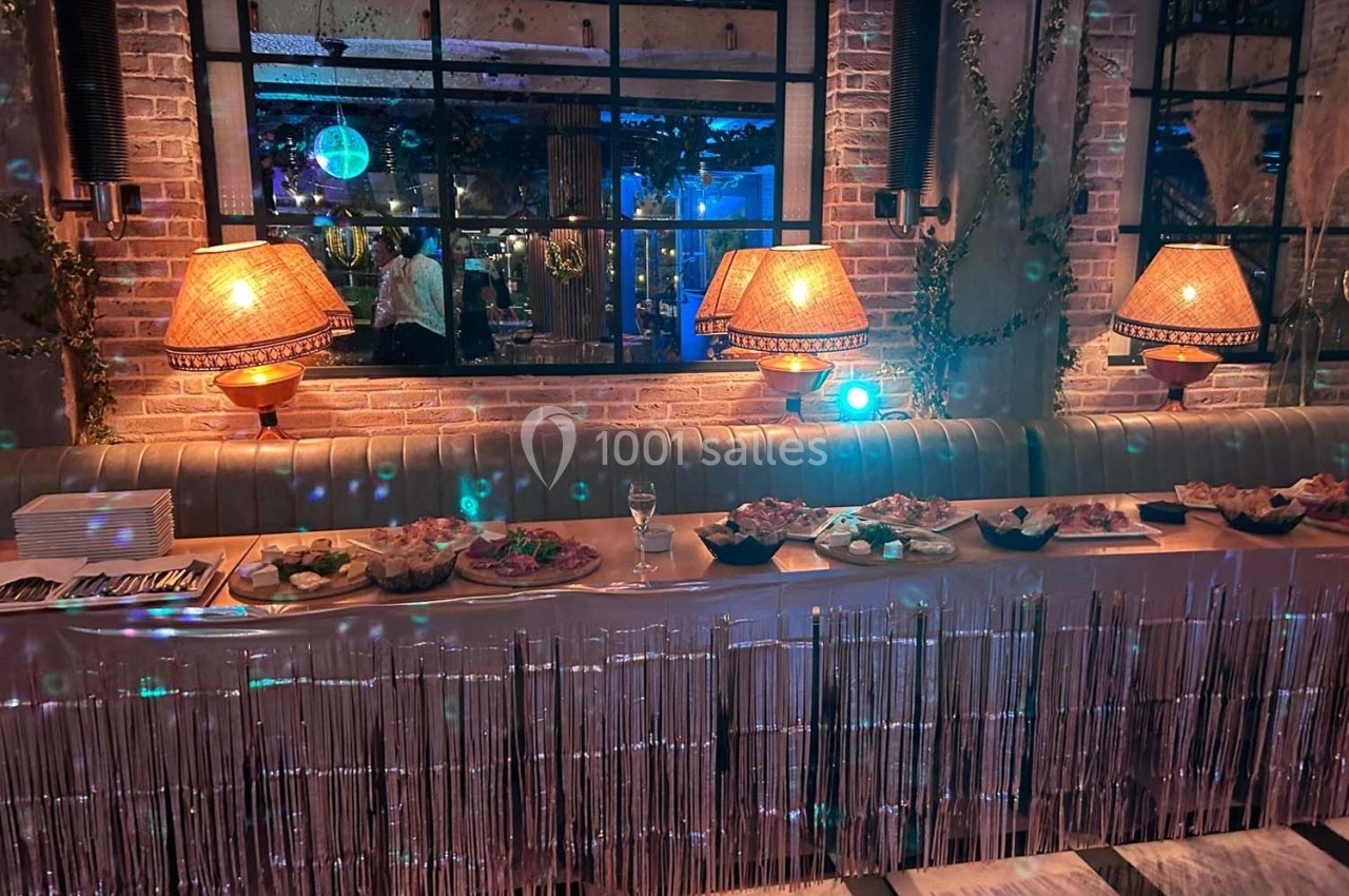 Buffet décoré avec des plats variés sur une table ornée de guirlandes, éclairée par des lampes et un éclairage tamisé.