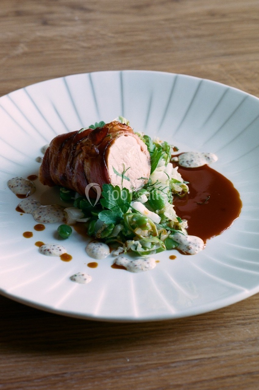 Plat gastronomique composé de viande roulée, légumes verts, sauce brune et crème, présenté sur une assiette blanche.