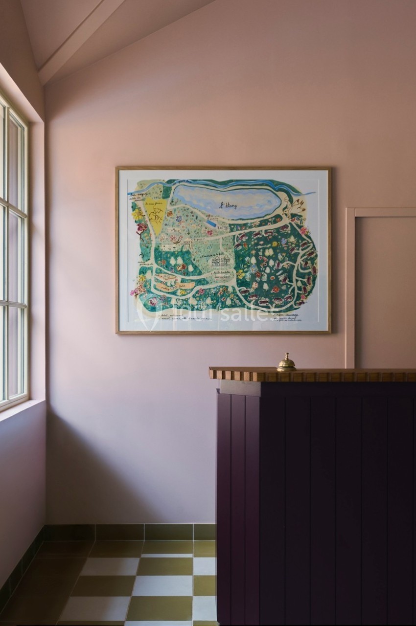 Carte illustrée encadrée accrochée au mur d'une pièce lumineuse avec un comptoir en bois violet au premier plan.