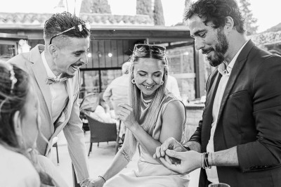 Trois personnes discutent et rient ensemble dans un cadre extérieur convivial.