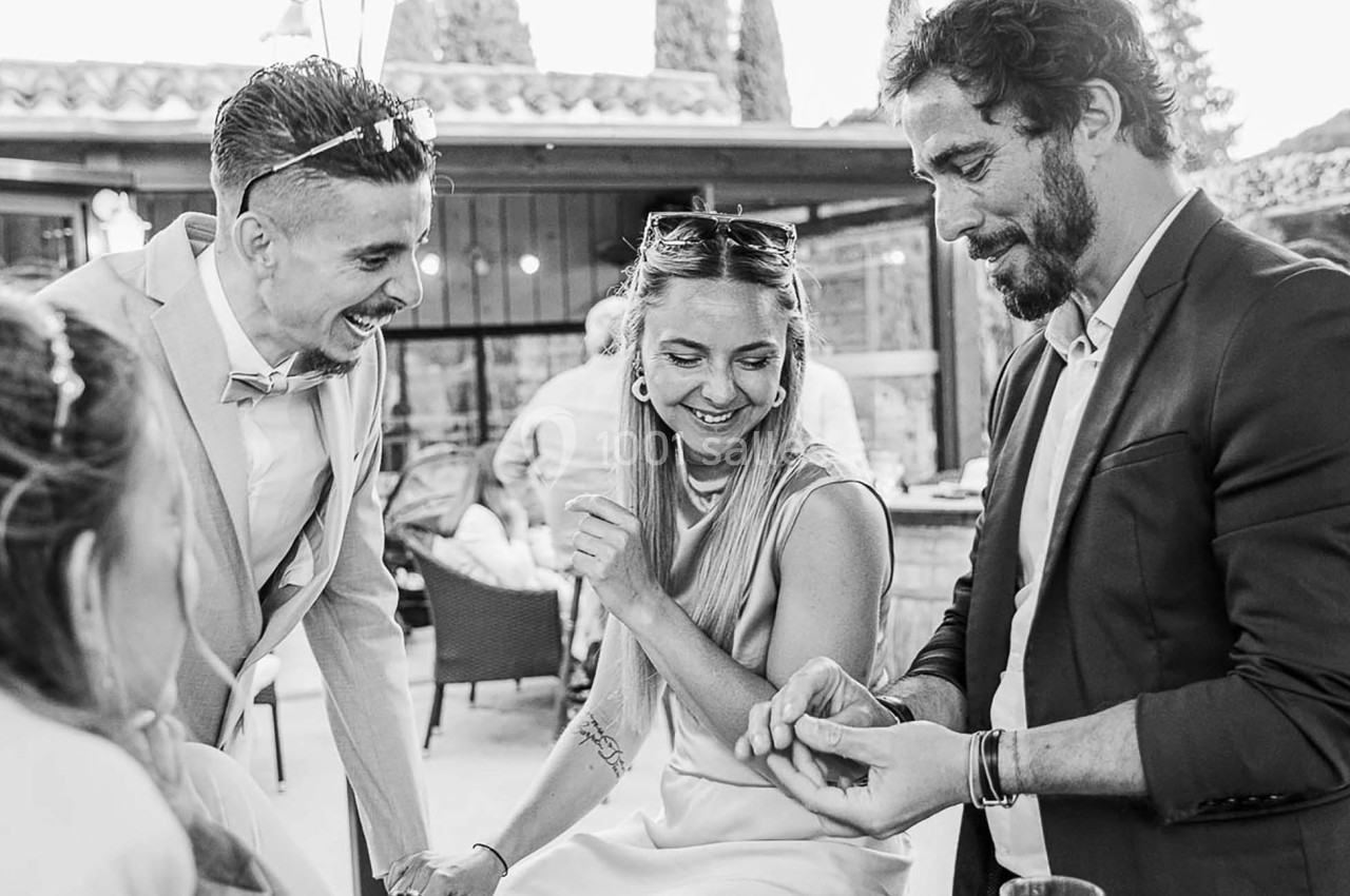 Trois personnes discutent et rient ensemble dans un cadre extérieur convivial.