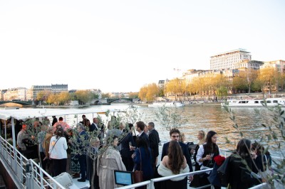 Miniature Location salle Paris 5 (Paris) - Péniche Amour #7 Terrasse d'un bateau aménagée avec des tables et des sièges, vue sur la tour Eiffel et un pont au coucher du soleil.