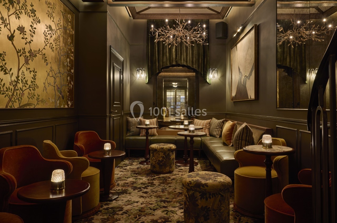 Salon élégant avec fauteuils, banquettes, tables basses, éclairage tamisé et décoration murale raffinée.