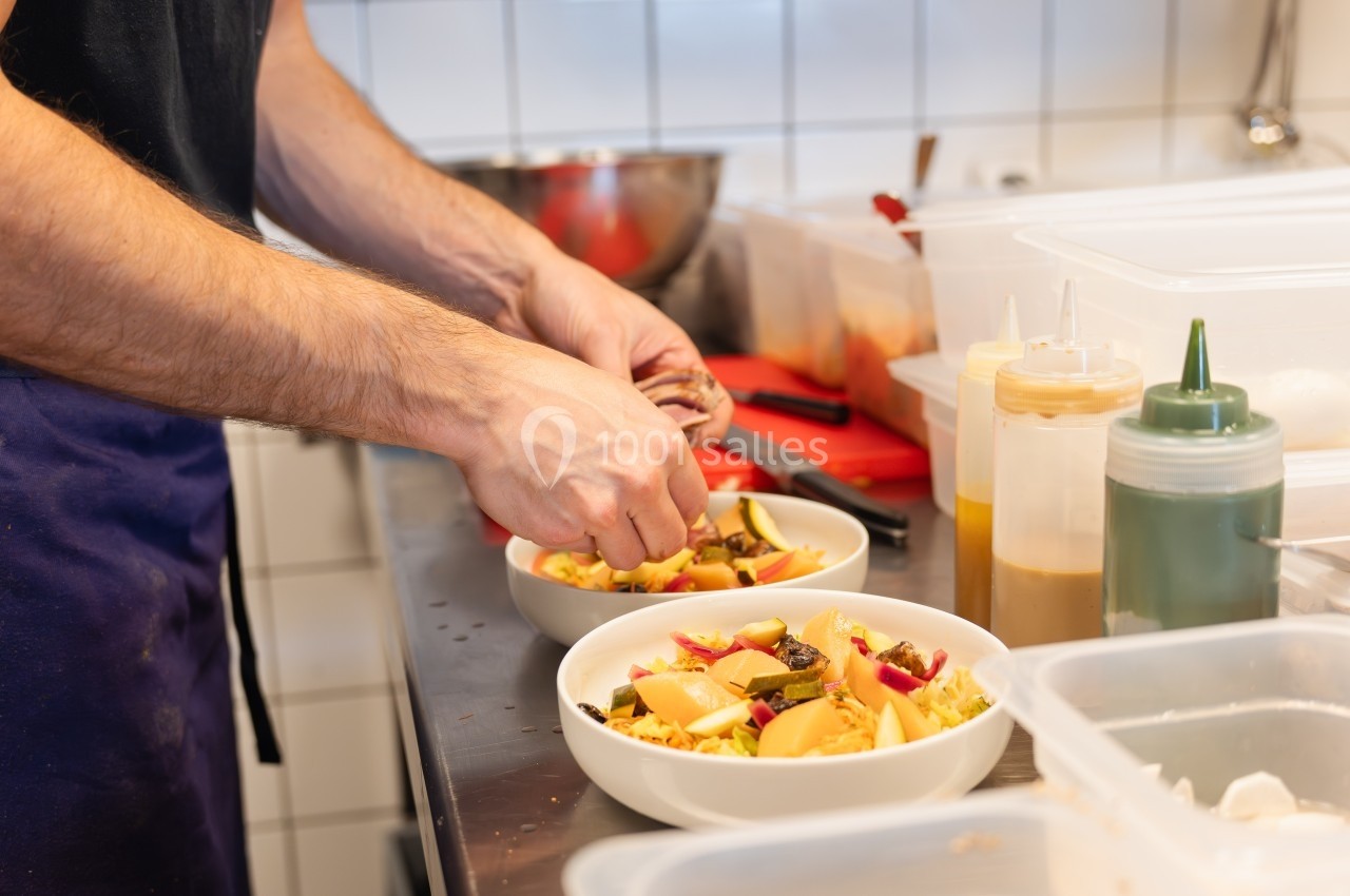 Un cuisinier prépare des assiettes de légumes colorés dans une cuisine professionnelle.