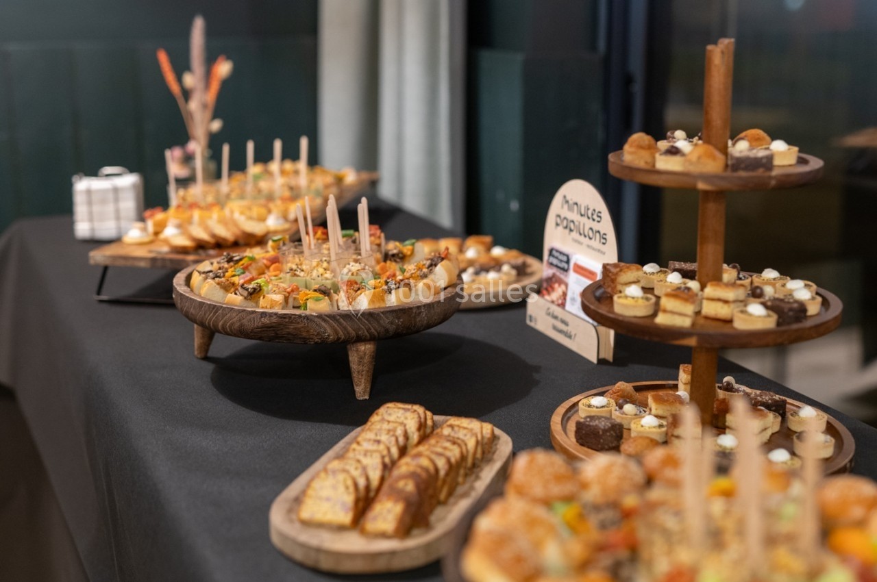 Buffet de pâtisseries et amuse-bouches variés présentés sur des plateaux en bois dans un cadre intérieur.