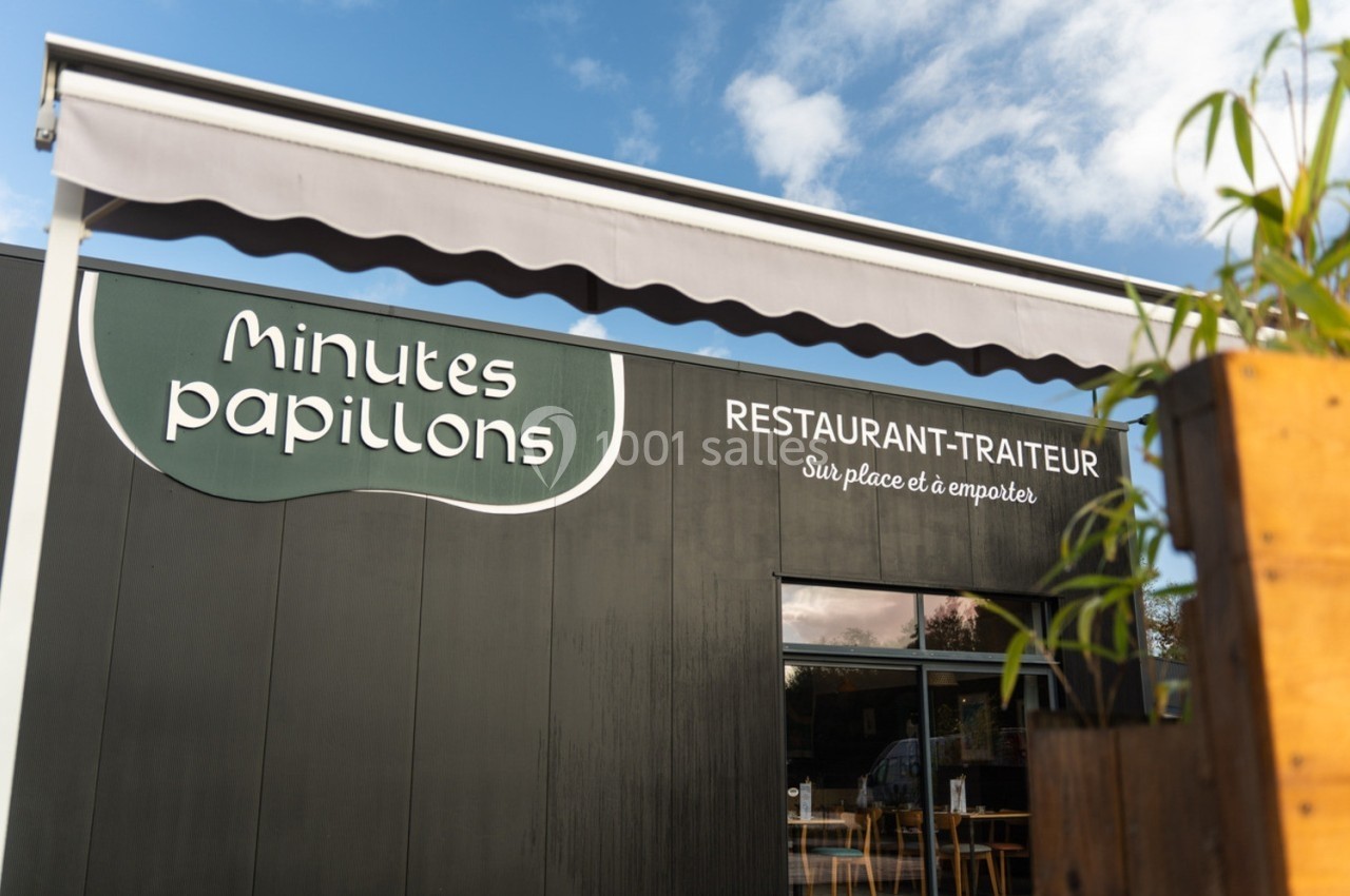 Façade d'un restaurant-traiteur nommé ’Minutes Papillons’ avec terrasse visible sous un ciel dégagé.
