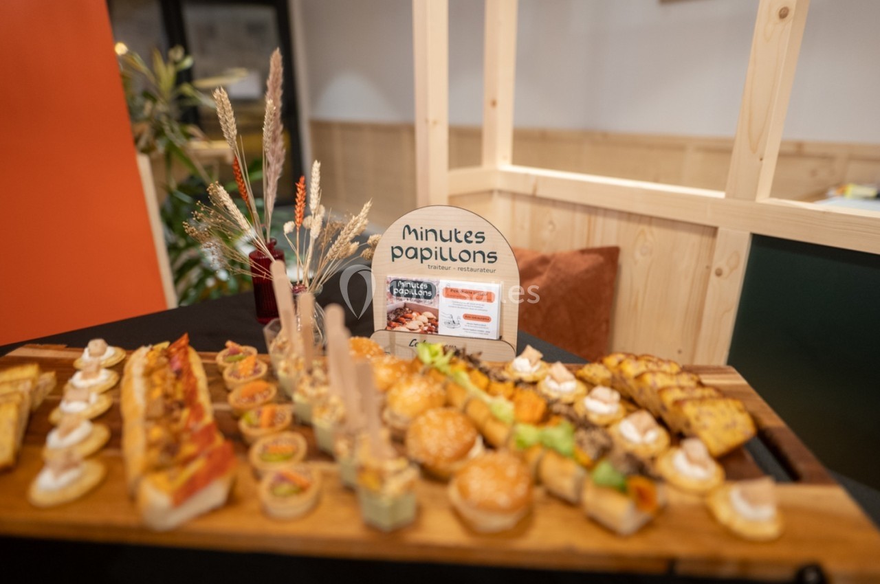 Plateau de bouchées variées disposées sur une table, avec un panneau indiquant ’Minutés papillons’ en arrière-plan.