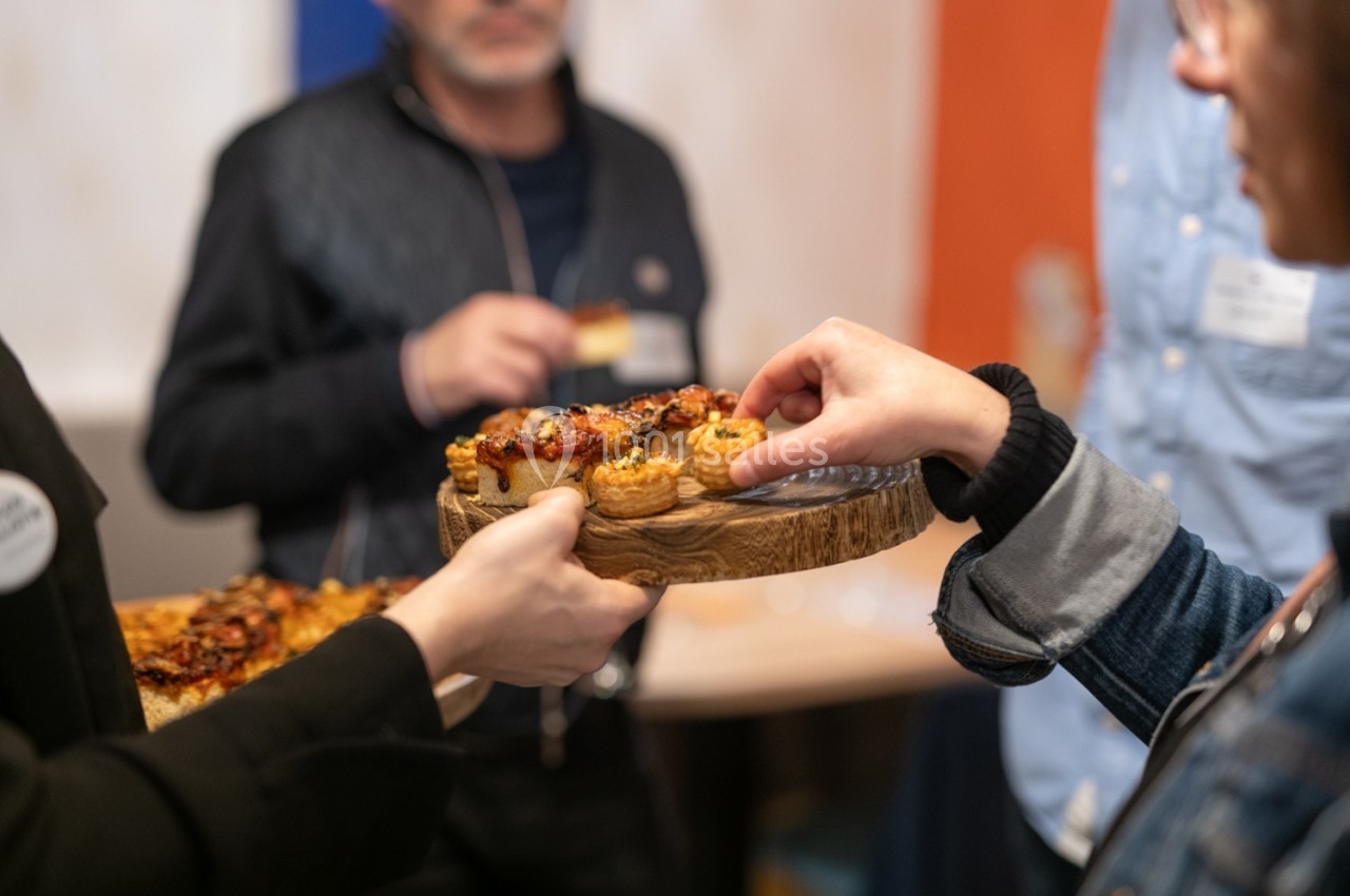 Des personnes se servant des amuse-bouches sur un plateau en bois lors d'un événement convivial.