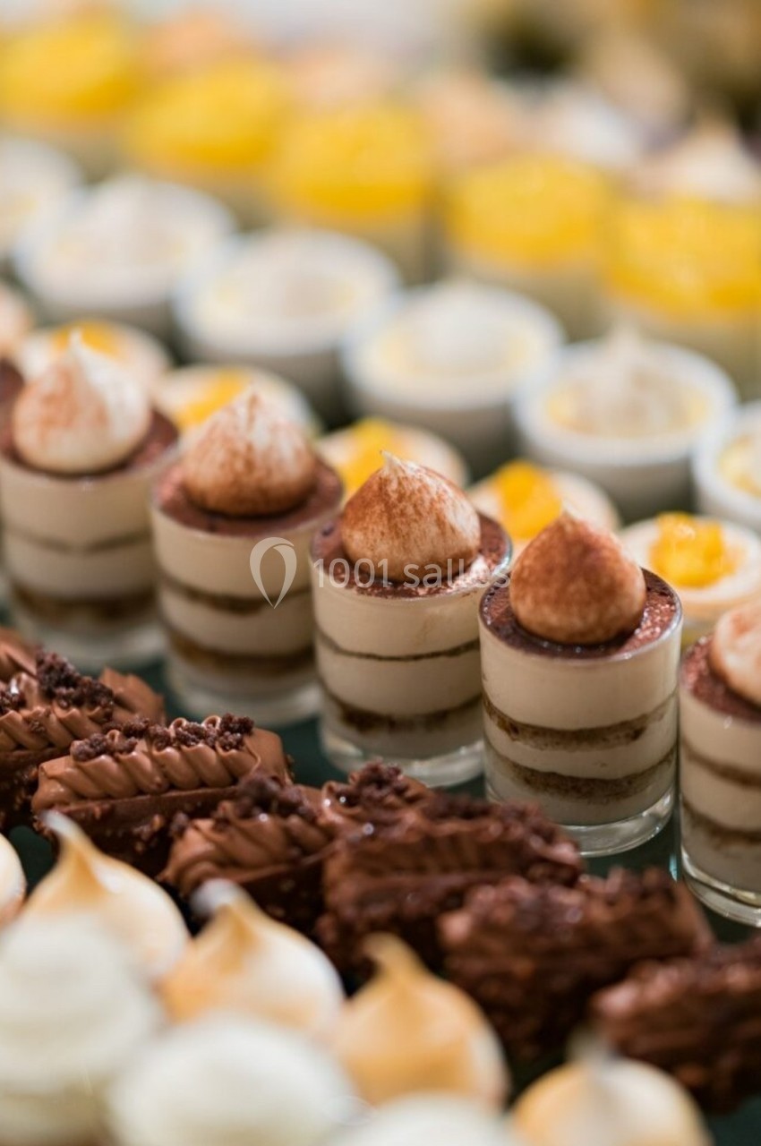 Desserts variés en verrines et pâtisseries, alignés sur une table, avec des couches de crème, chocolat et fruits.