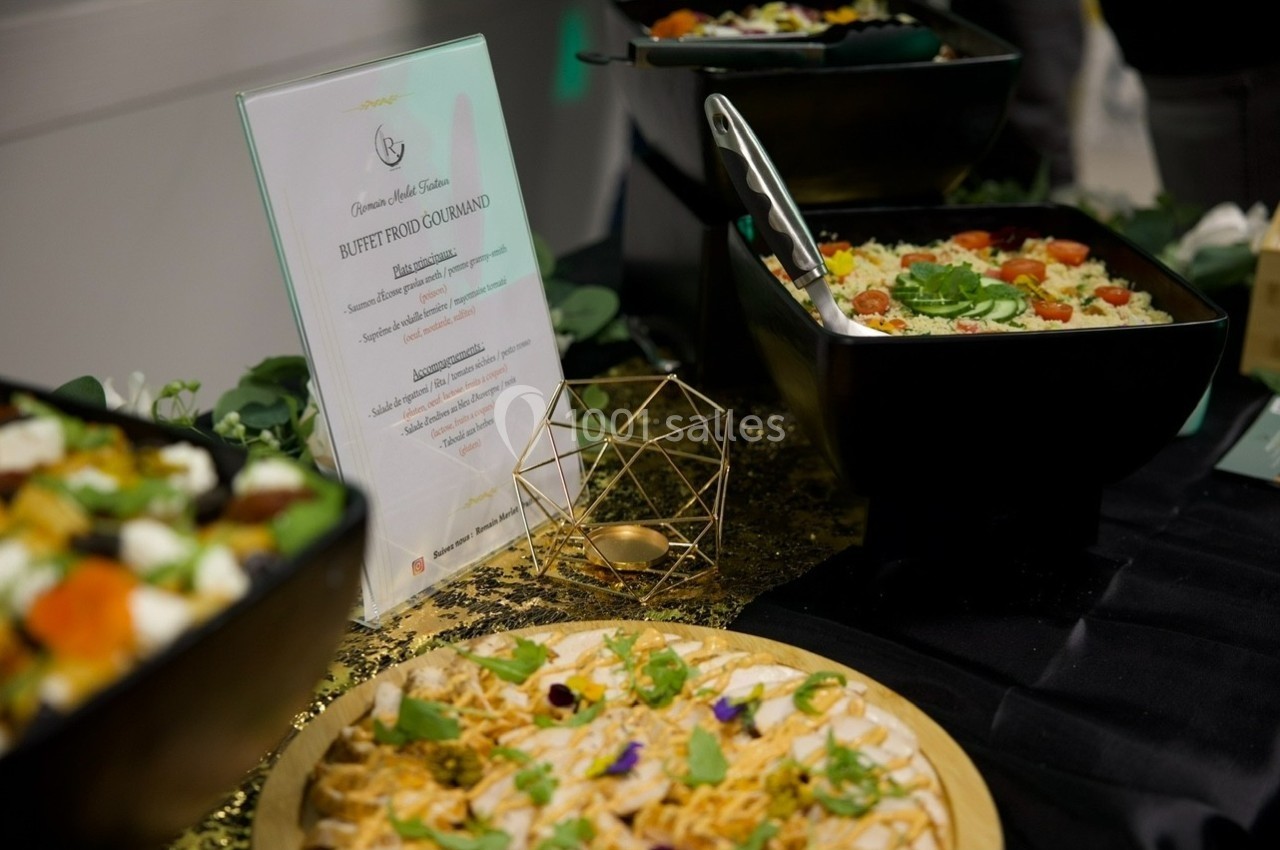 Buffet composé de plats variés, incluant des salades et un plat garni de fleurs comestibles, présenté sur une table décorée.