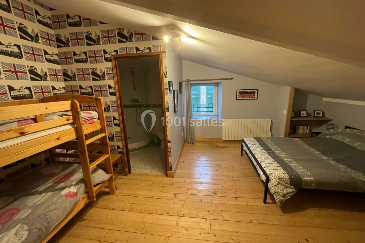 Chambre mansardée avec lit double, lits superposés, parquet en bois et salle de bain attenante.