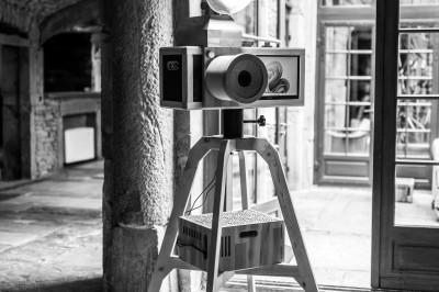 Téléphone rétro doré à cadran rotatif posé sur une surface blanche, avec un décor en bois et pierre en arrière-plan.