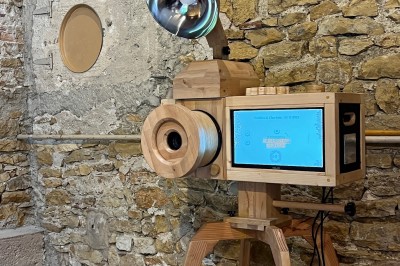 Téléphone rétro doré à cadran rotatif posé sur une surface blanche, avec un décor en bois et pierre en arrière-plan.