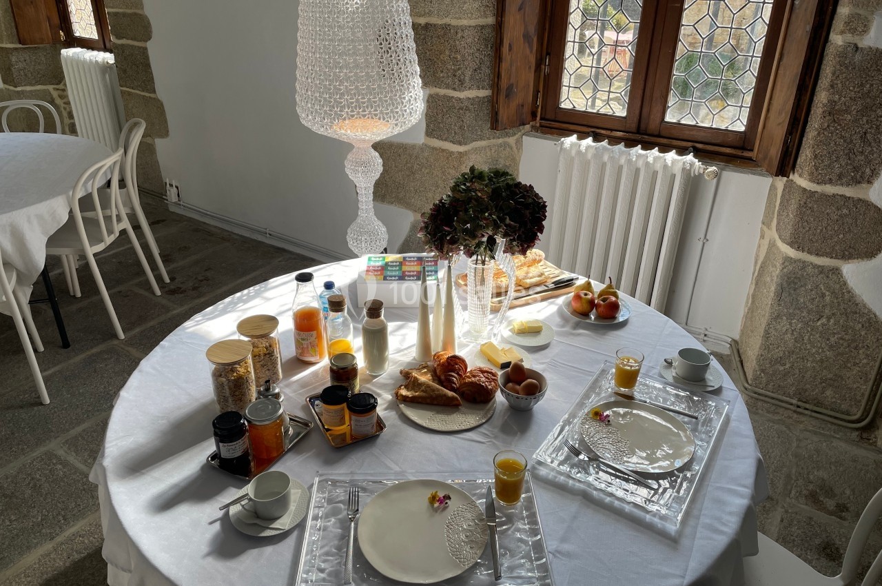 Table dressée pour un petit-déjeuner avec viennoiseries, fruits, jus d'orange, confitures et boissons chaudes.