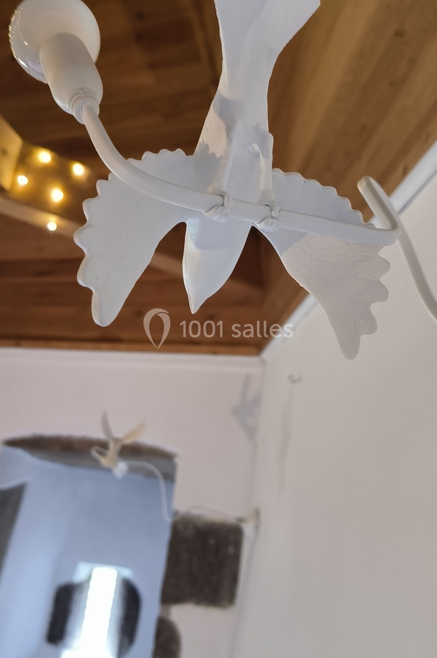 Suspension en forme d'oiseau blanc avec des ailes déployées, accrochée dans une pièce au plafond en bois.