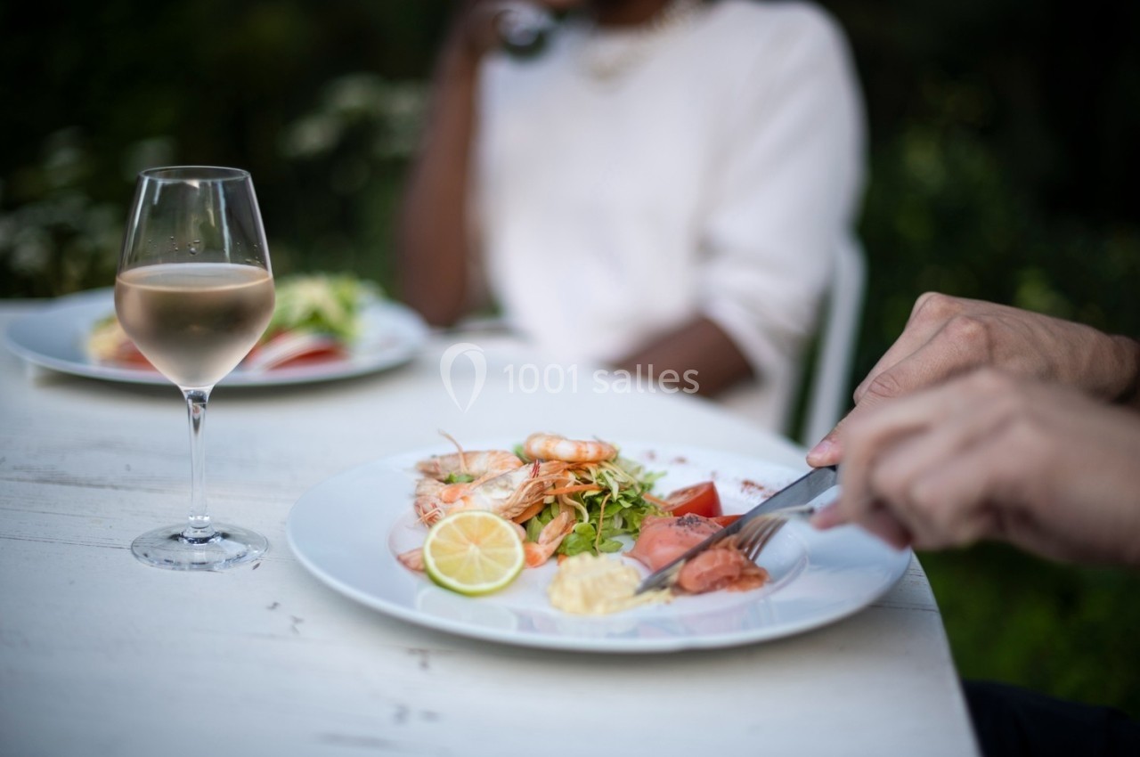 Assiette de fruits de mer avec crevettes, saumon fumé, citron et salade, sur une table avec un verre de vin rosé.