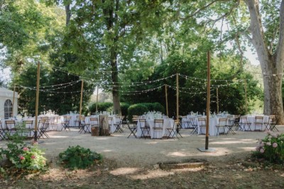 Table dressée avec nappes blanches, vaisselle vintage, chandeliers et décorations florales séchées.