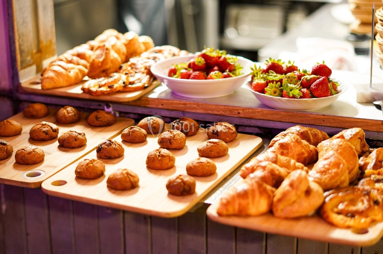 Pâtisseries variées, croissants, biscuits et bols de fraises fraîches disposés sur un comptoir en bois.
