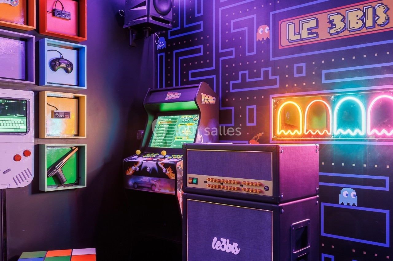 Salle rétro avec borne d'arcade, amplificateurs, étagères d'objets vintage et décor inspiré de jeux vidéo.