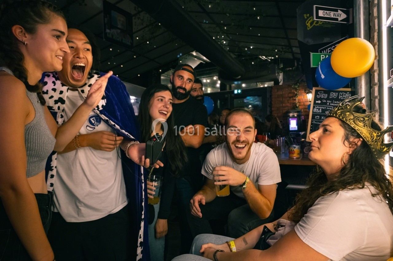 Un groupe de personnes souriantes dans un bar, certaines déguisées, partageant un moment convivial.